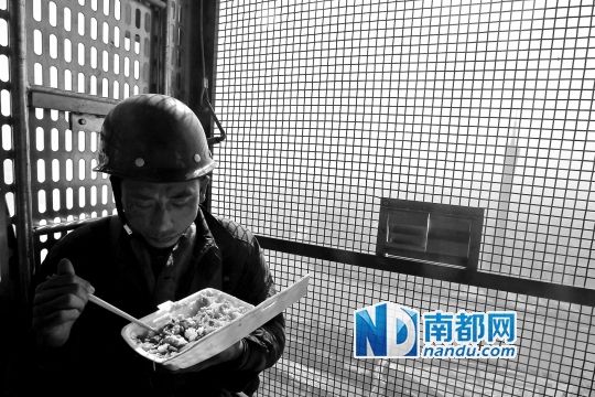 东塔封顶在即,为节约时间,一工人在工程电梯里吃饭。 东塔封顶在即,为节约时间,一工人在工程电梯里吃饭。